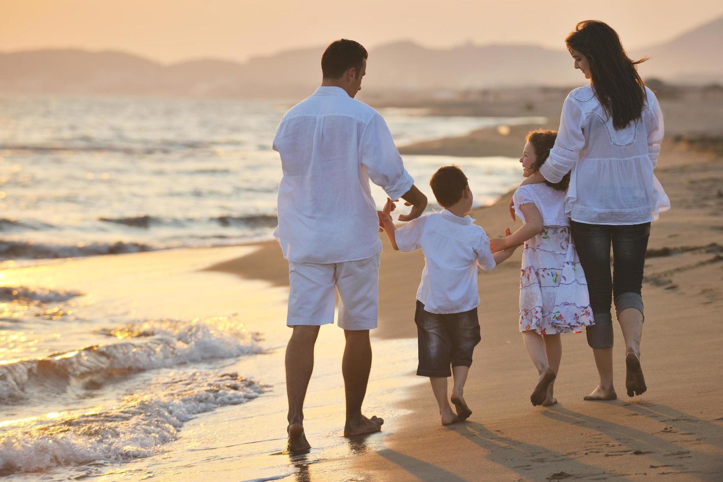 glückliche junge familie hat spaß am strand bei sonnenuntergang foto