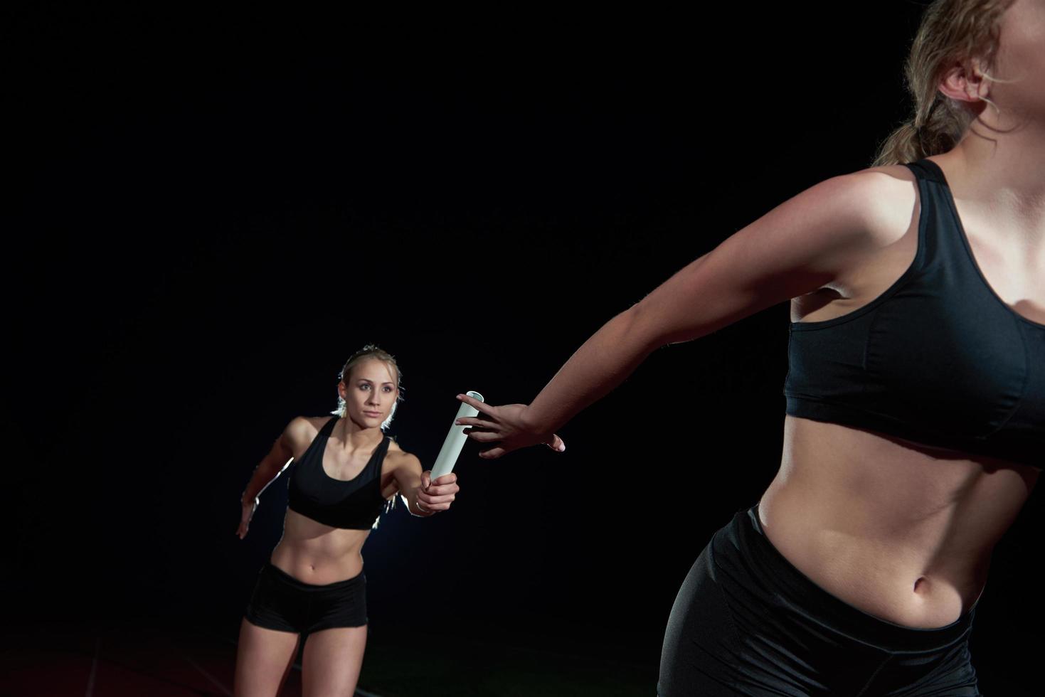 athletische läufer, die den stab im staffellauf übergeben foto