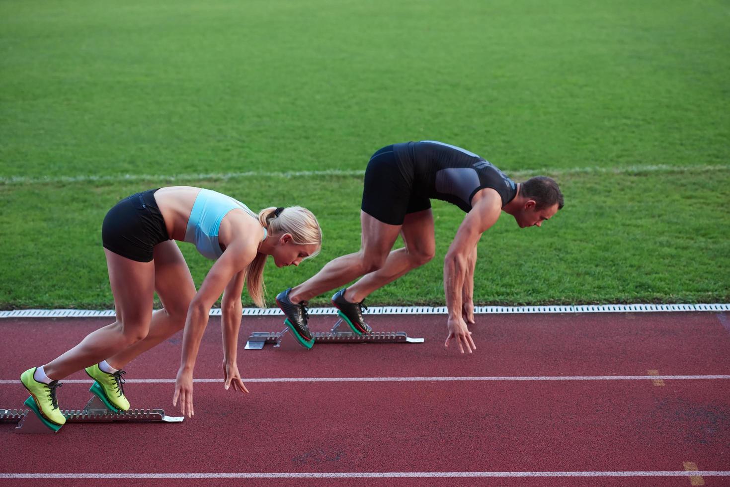 athletinnengruppe, die auf leichtathletik-rennstrecke läuft foto