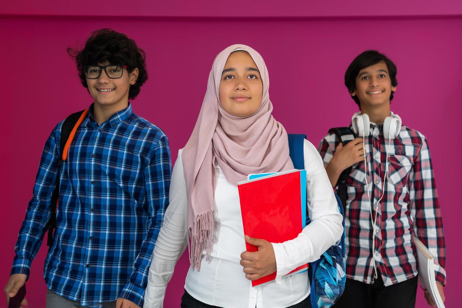 eine gruppe arabischer teenager, ein studententeam, das in die zukunft und zurück zur schule geht, das konzept eines rosa hintergrunds. das Konzept einer erfolgreichen Bildung für junge Menschen. selektiver Fokus foto