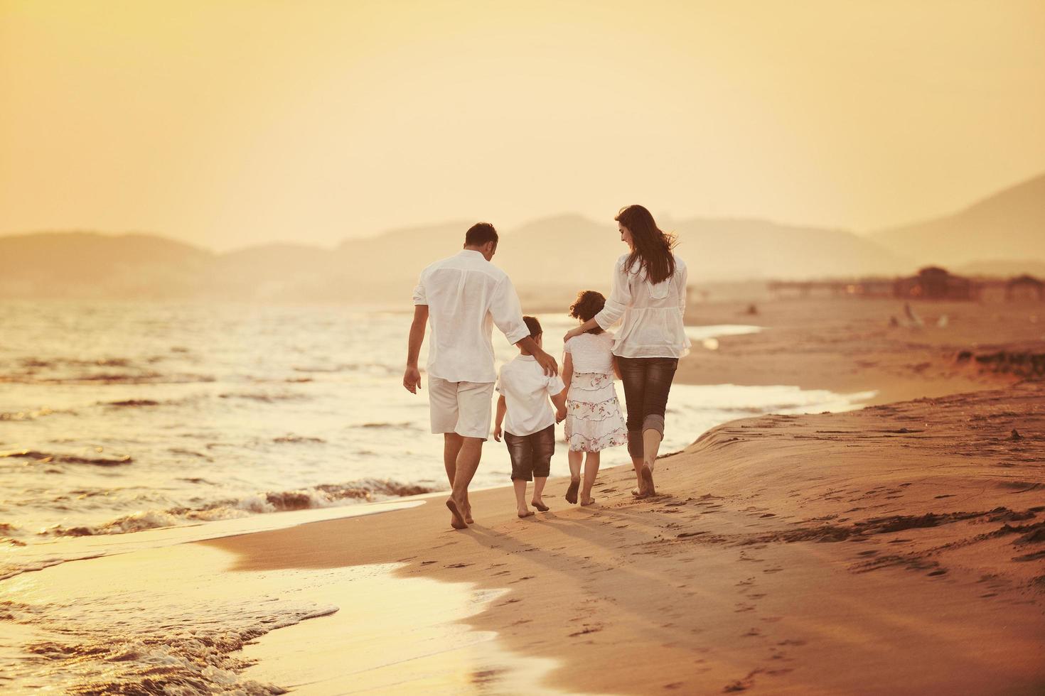 glückliche junge familie hat spaß am strand bei sonnenuntergang foto