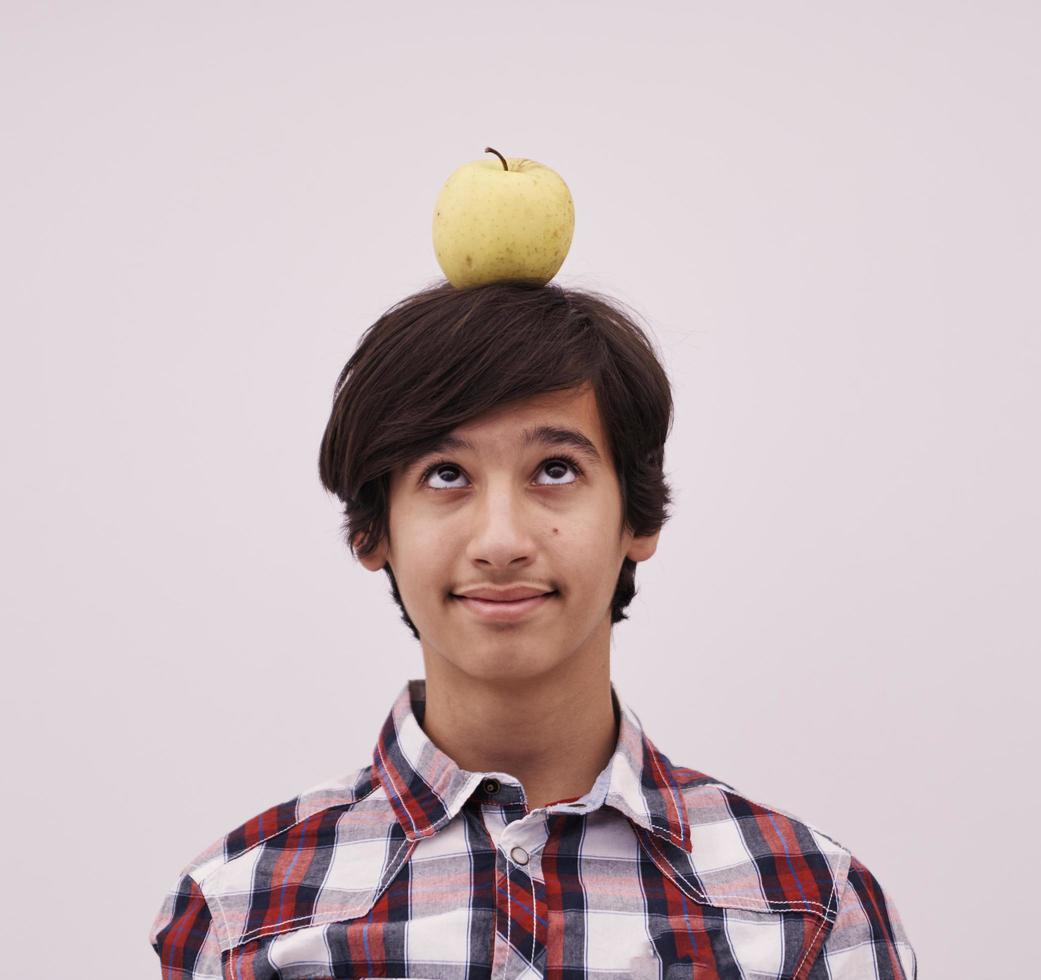 Porträt eines jungen Teenagers mit einem Apfel auf dem Kopf foto