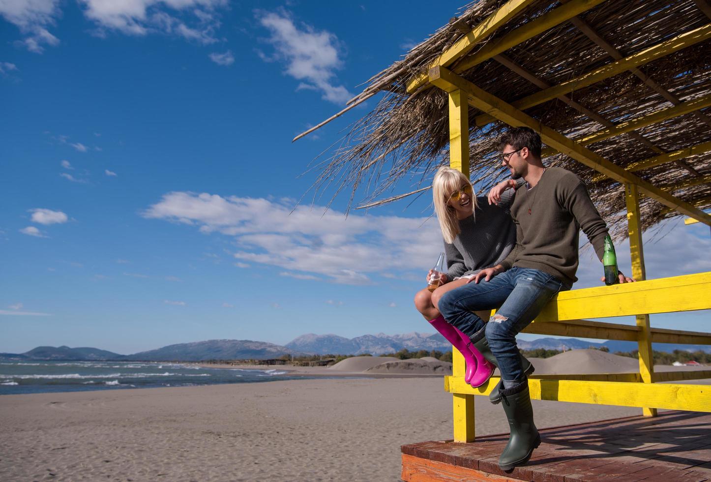 junges Paar trinkt gemeinsam Bier am Strand foto