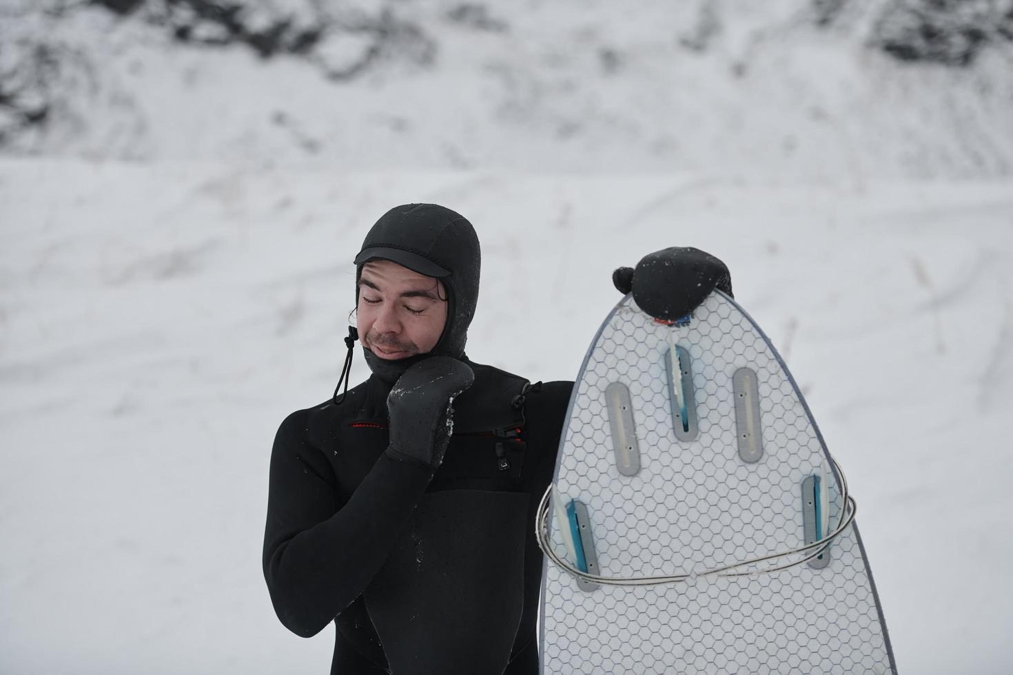 arktisches surferporträt, das ein brett nach dem surfen im norwegischen meer hält foto