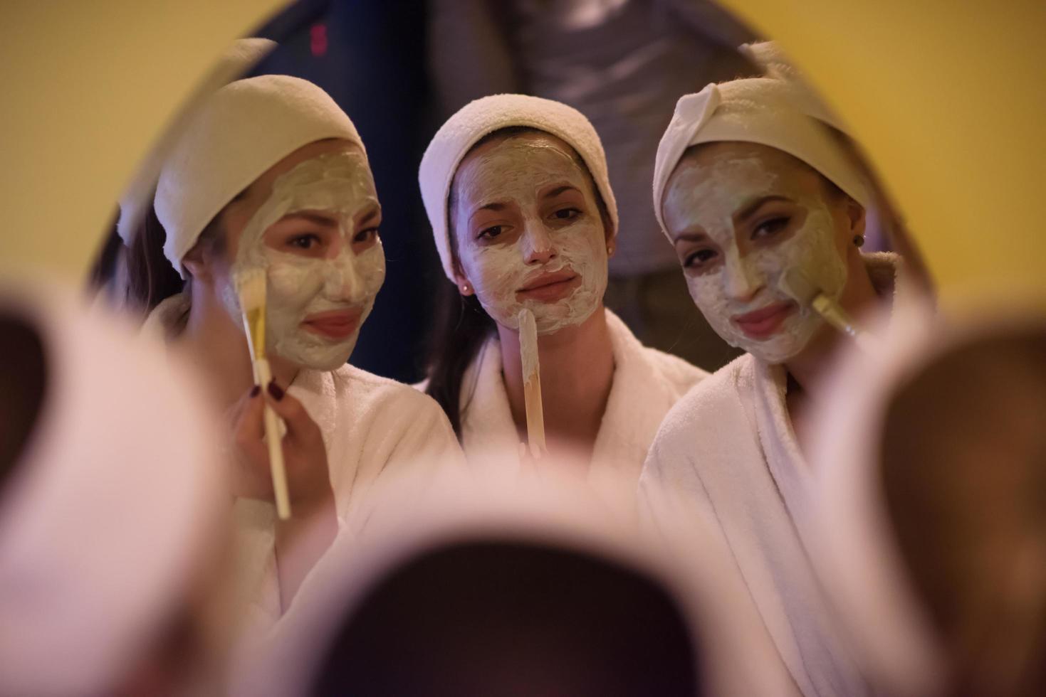 Frauen, die Gesichtsmasken ins Badezimmer legen foto