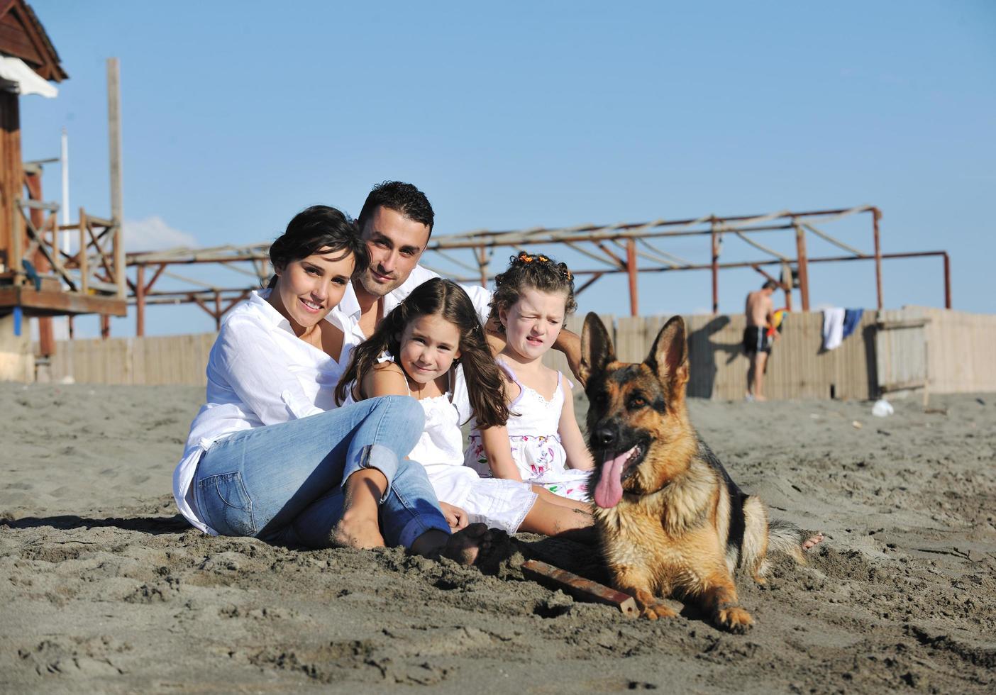 glückliche familie, die mit hund am strand spielt foto