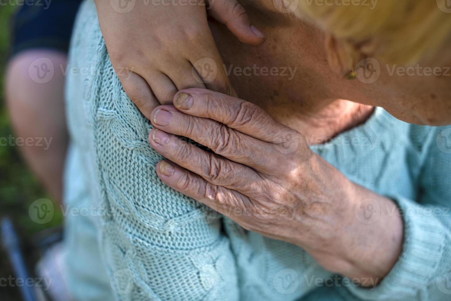 Reife weibliche Großmutter hält die Hände ihres Enkels, foto