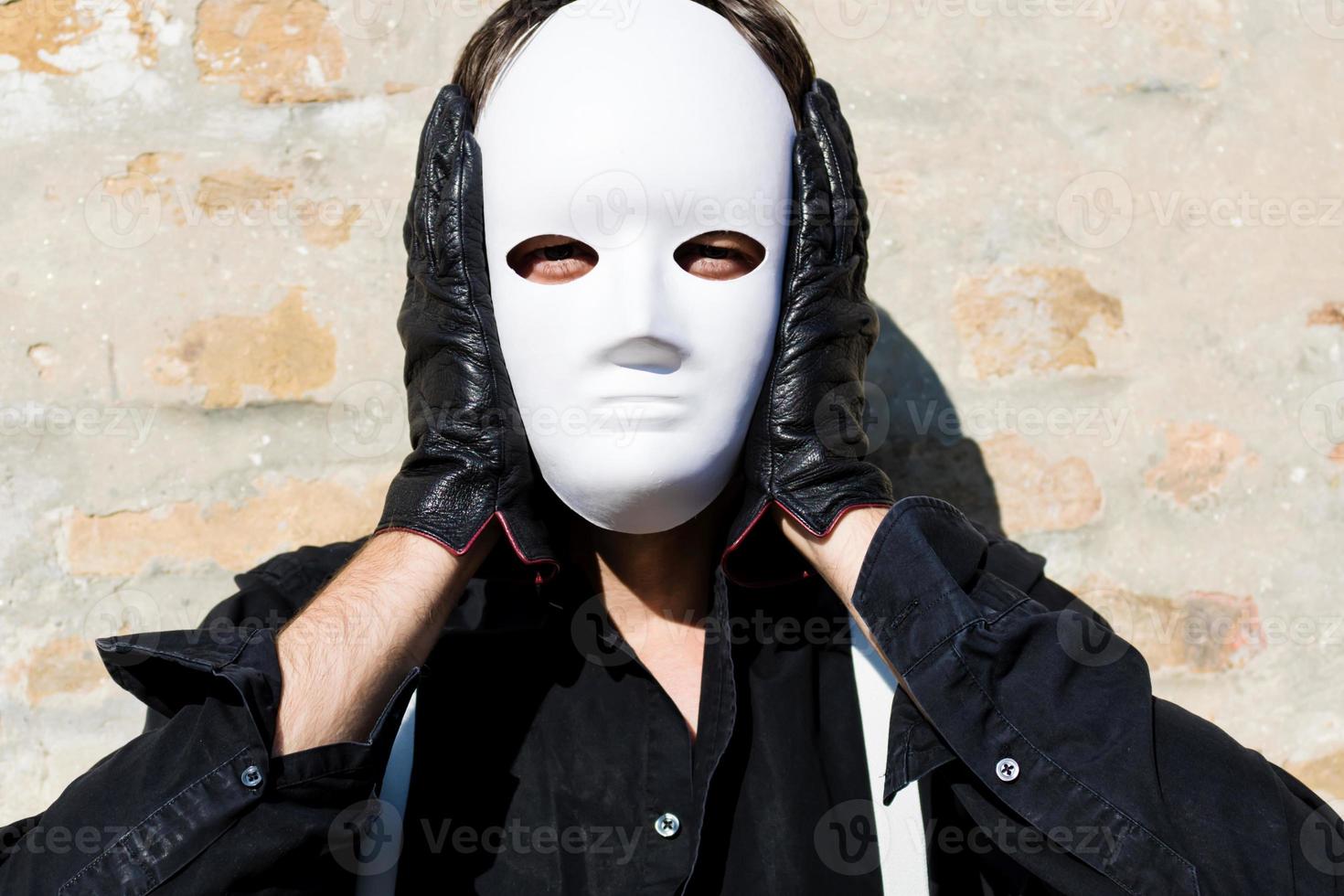 Mann, der eine weiße Maske auf seinem Gesicht hält und in die Kamera schaut. foto