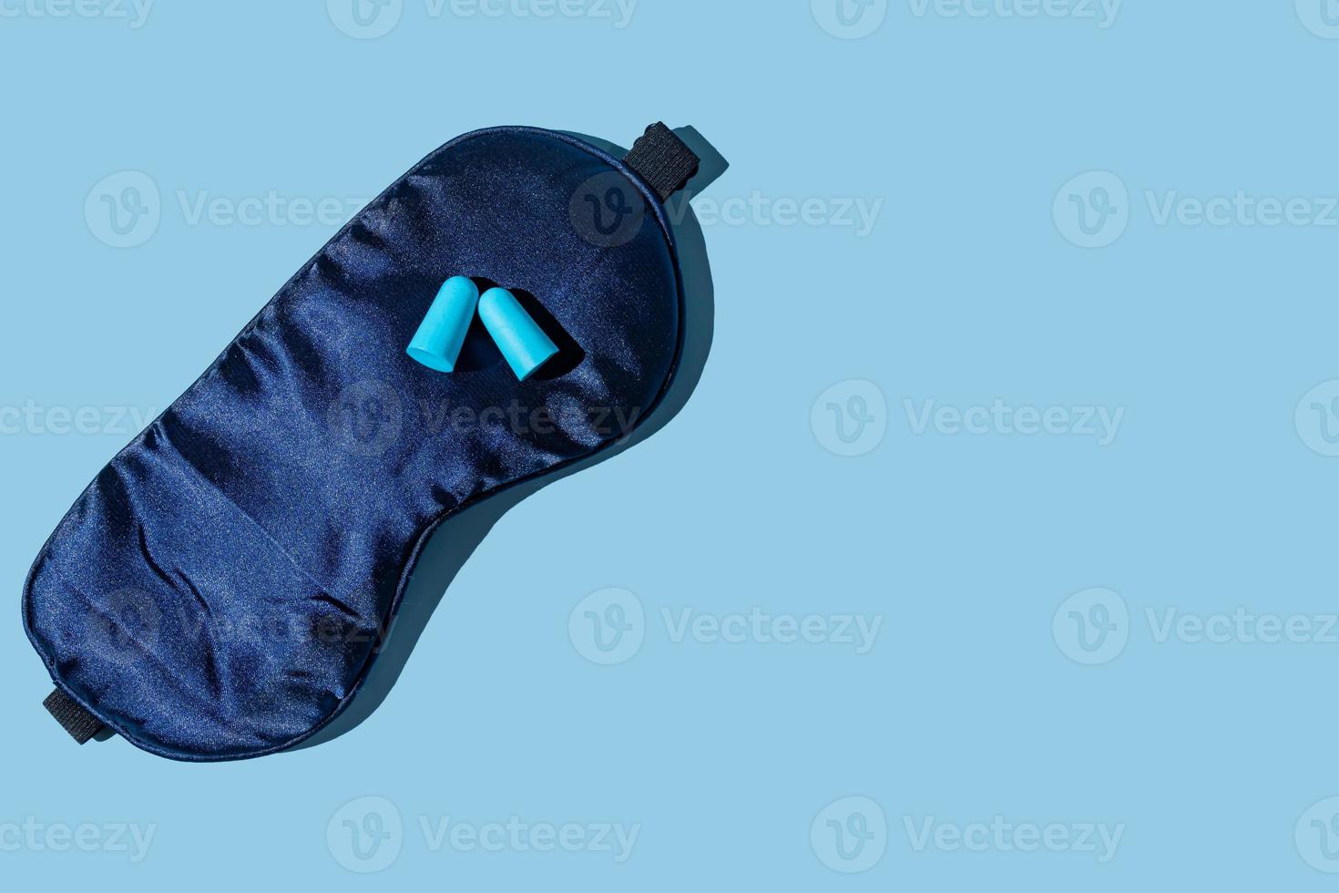 Paar blaue Ohrstöpsel und Schlafmaske auf hellblauem Hintergrund, flach mit Kopierraum foto
