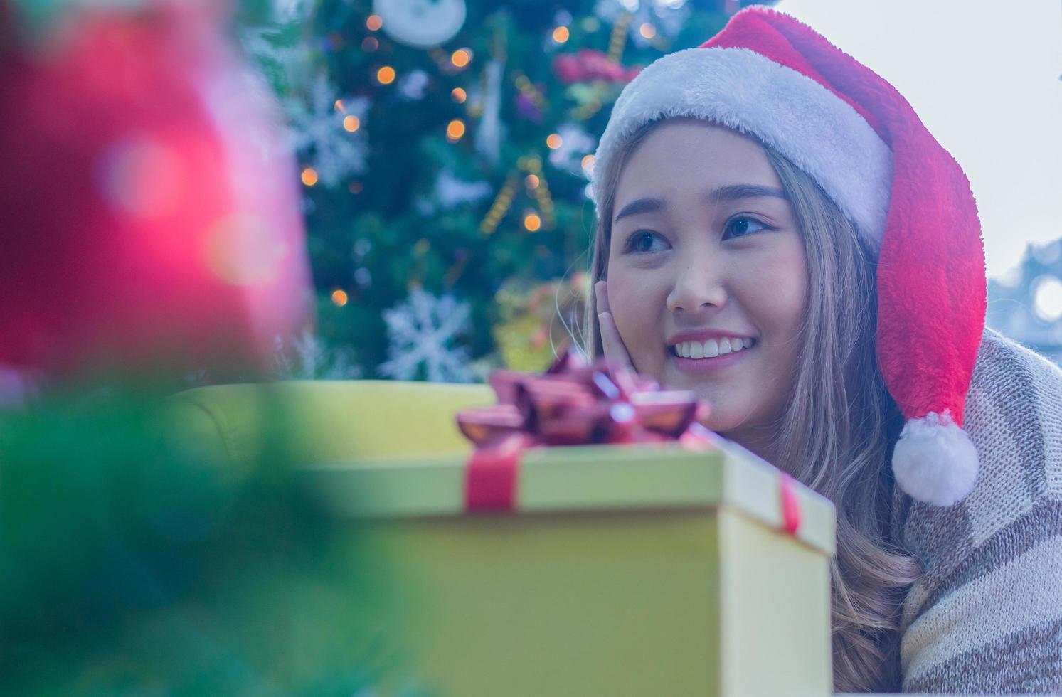 Frau lächelt in der Nähe von Weihnachtsgeschenk foto