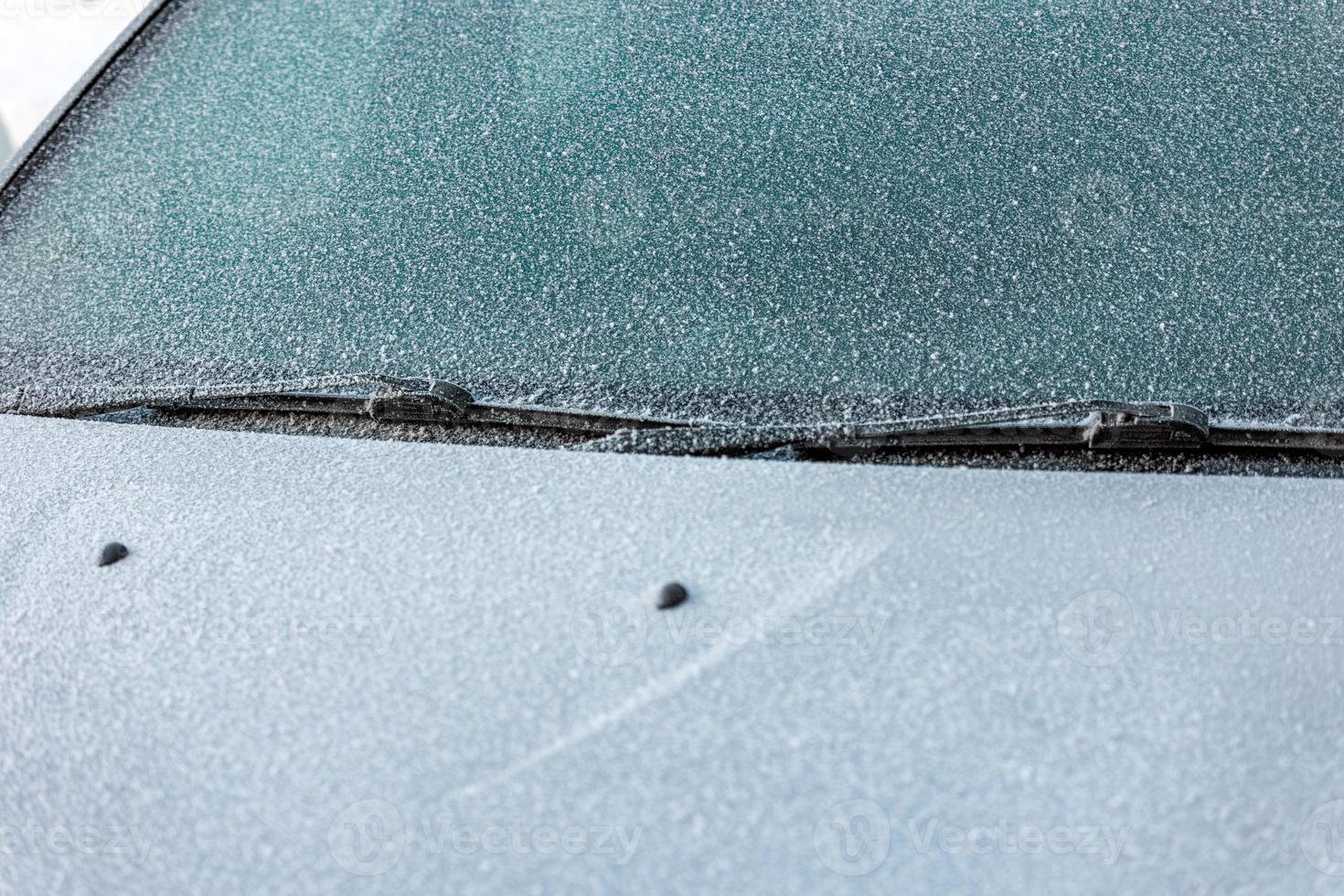 Frost bedeckte weiße Motorhaube, Scheibenwischer und Windschutzscheibe - Nahaufnahmehintergrund mit selektivem Fokus foto