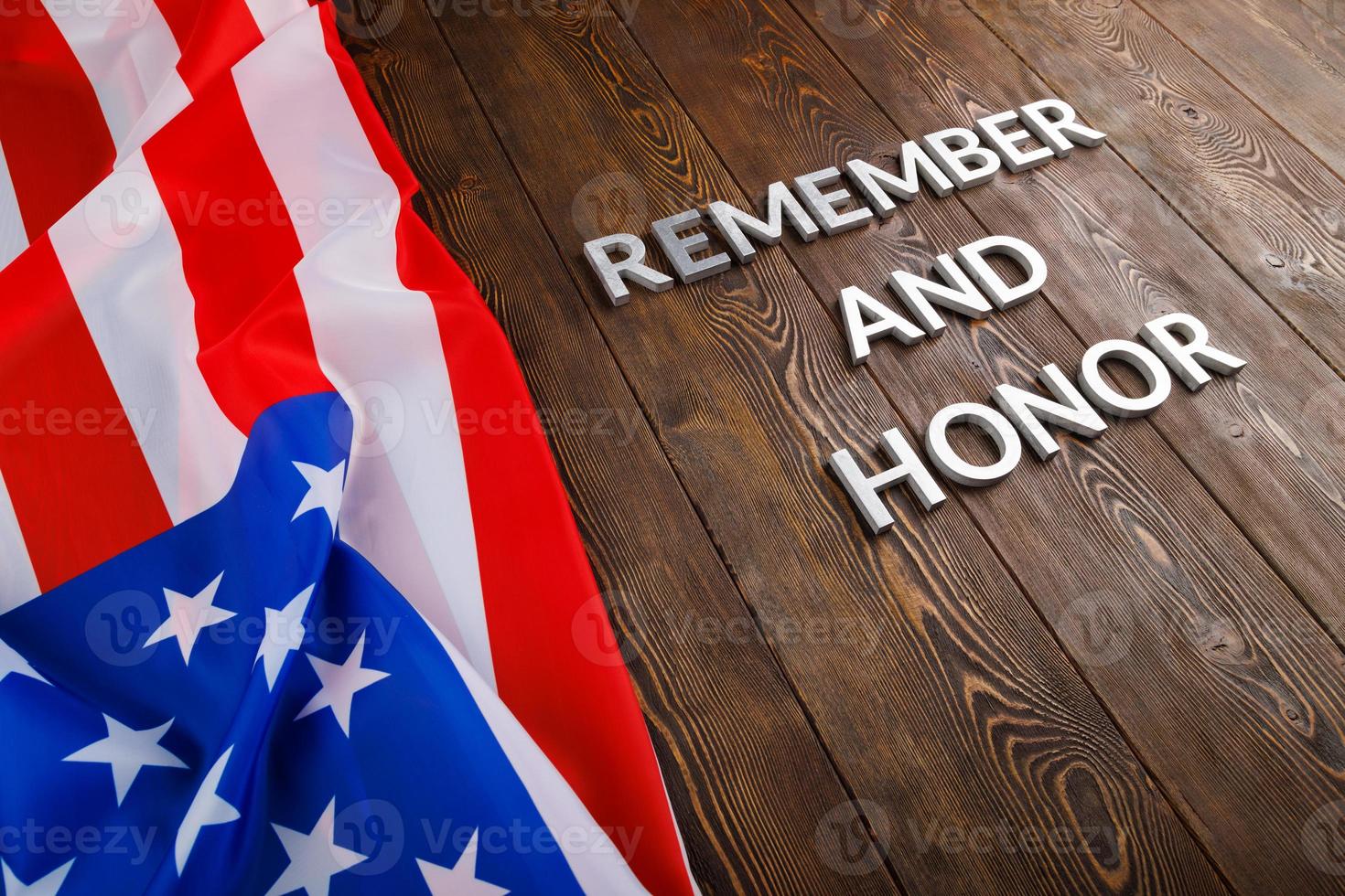 worte erinnern und ehren mit silbernen metallbuchstaben auf hölzernem hintergrund mit usa-flagge auf der linken seite foto