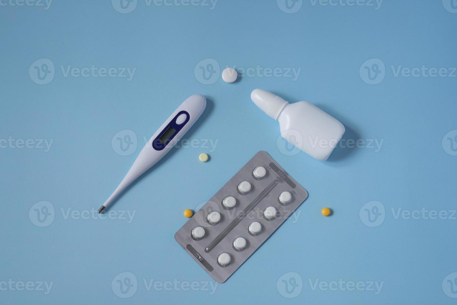 Draufsicht auf Medikamente, Thermometer auf blauem, blauem Hintergrund. er lag flach. Erste-Hilfe-Kasten - Pillen, Thermometer, Tropfen. flach liegend. Tabletten in einer Packung. Tabletten sind weiß und gelb. foto