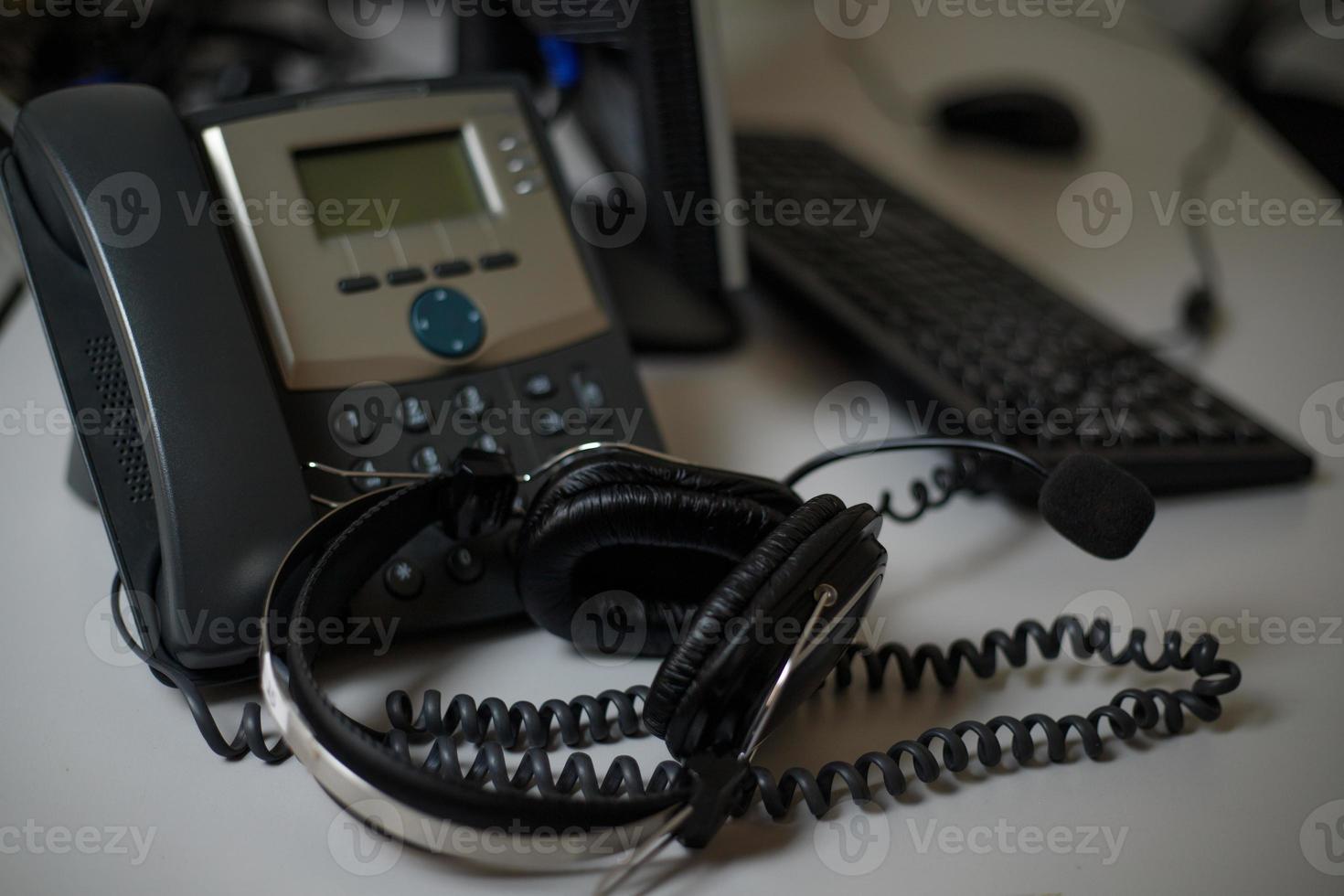 stationäres Telefon und Headset auf dem Schreibtisch im Innenbereich, Nahaufnahme. Kommunikationsunterstützung, Call Center und Kundendienst. foto