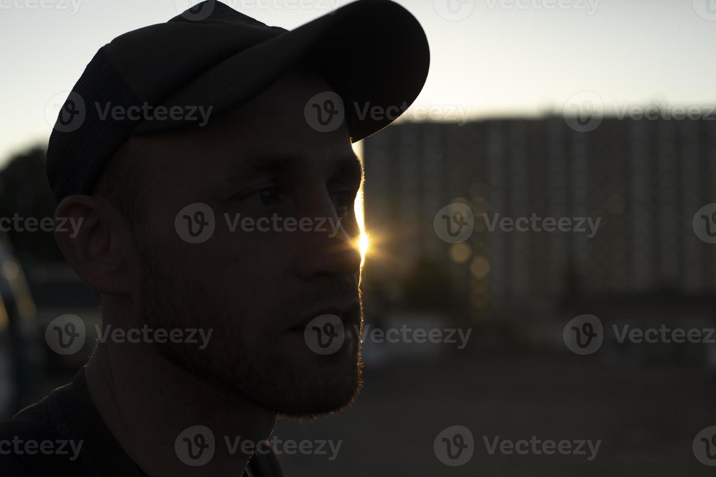 Typ mit Mütze bei Sonnenuntergang. Mann auf der Straße. foto