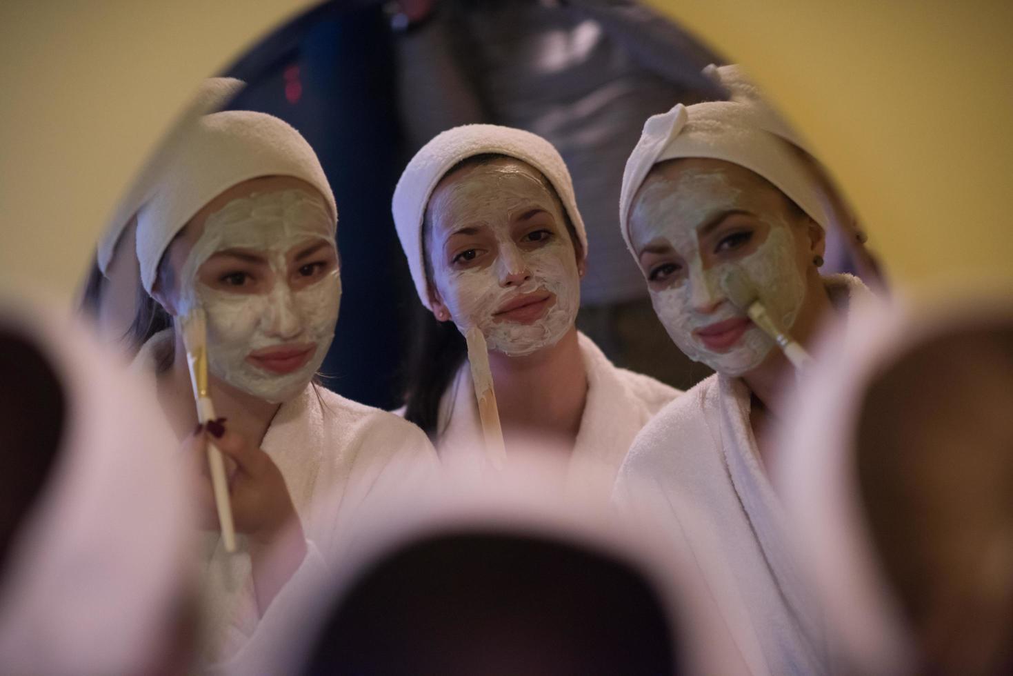 Frauen, die Gesichtsmasken ins Badezimmer legen foto