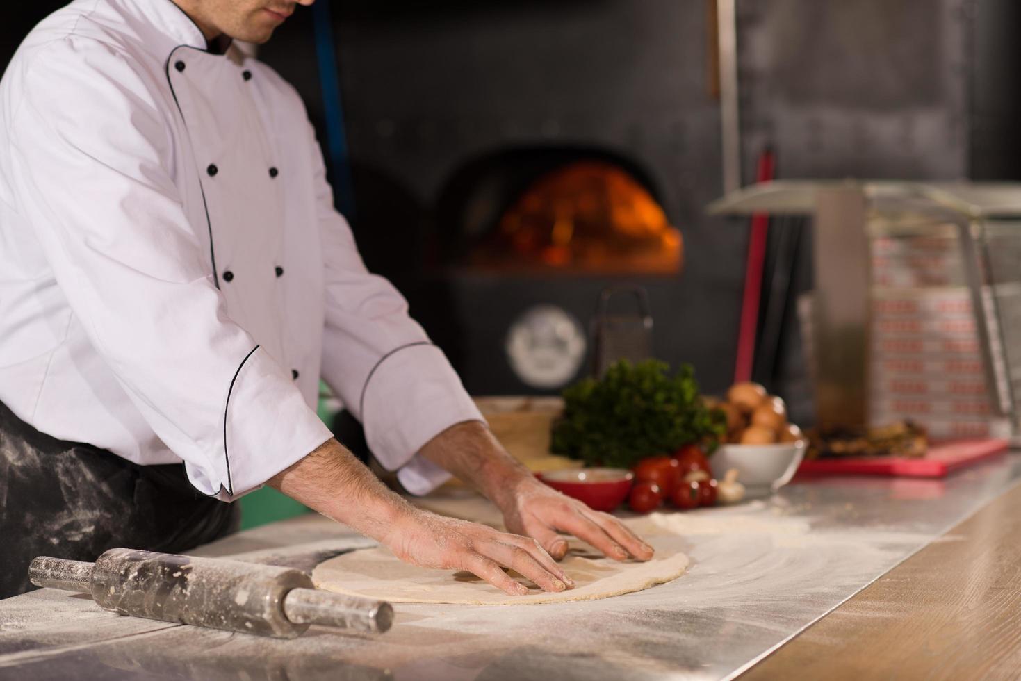 koch bereitet teig für pizza zu foto