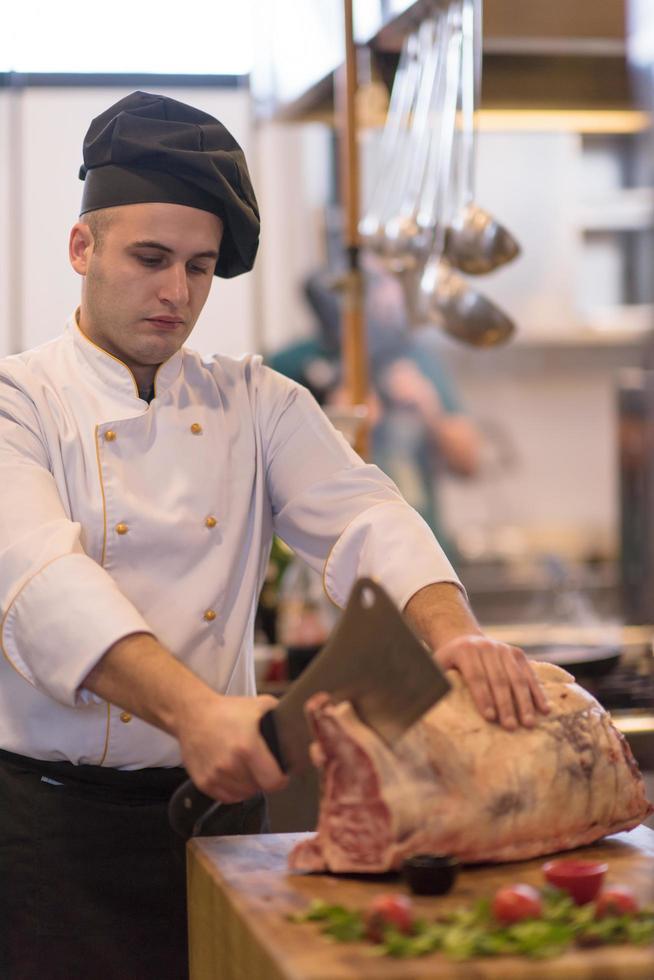 Koch schneidet ein großes Stück Rindfleisch foto