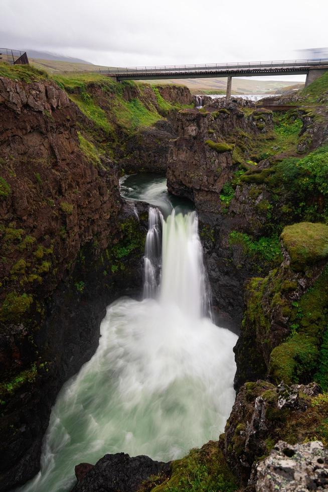 Wasserfall unter einer Brücke in Island foto