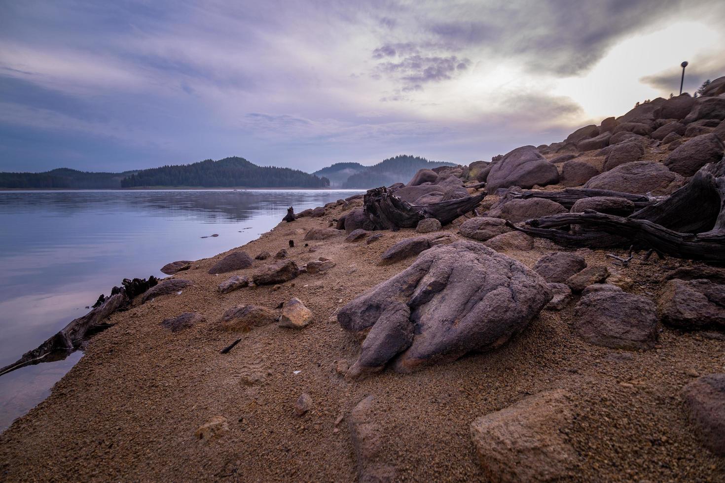 Felsen an einem Ufer mit Bergen foto