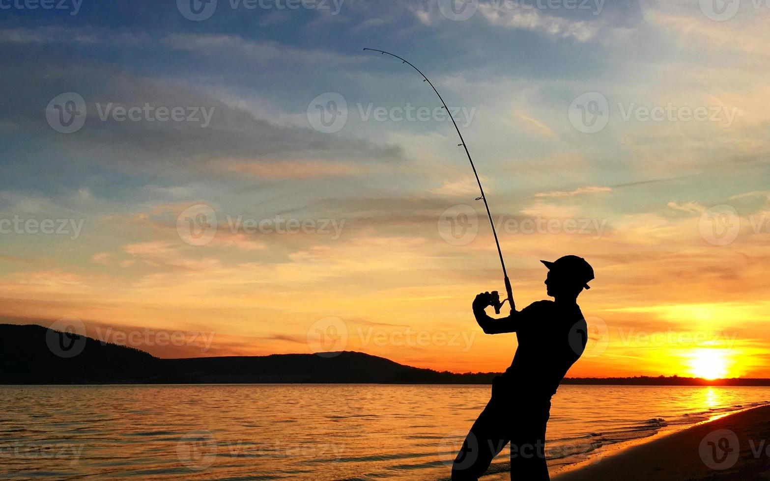 junger Mann beim Angeln bei Sonnenuntergang foto