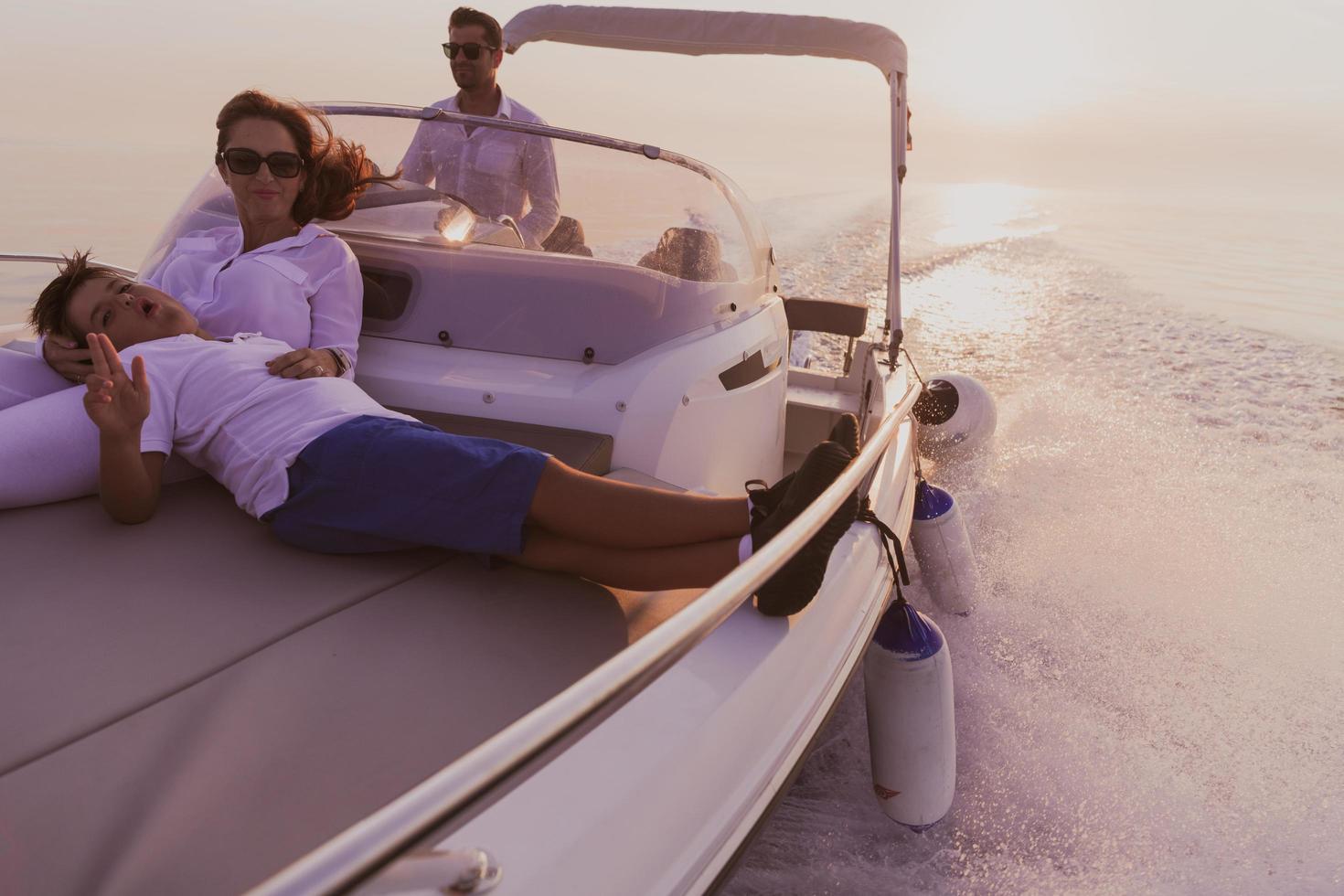 ein älteres paar in lässigen outfits mit ihrem sohn genießt es, bei sonnenuntergang auf einem boot auf see zu fahren. das Konzept einer glücklichen Familie. selektiver Fokus foto