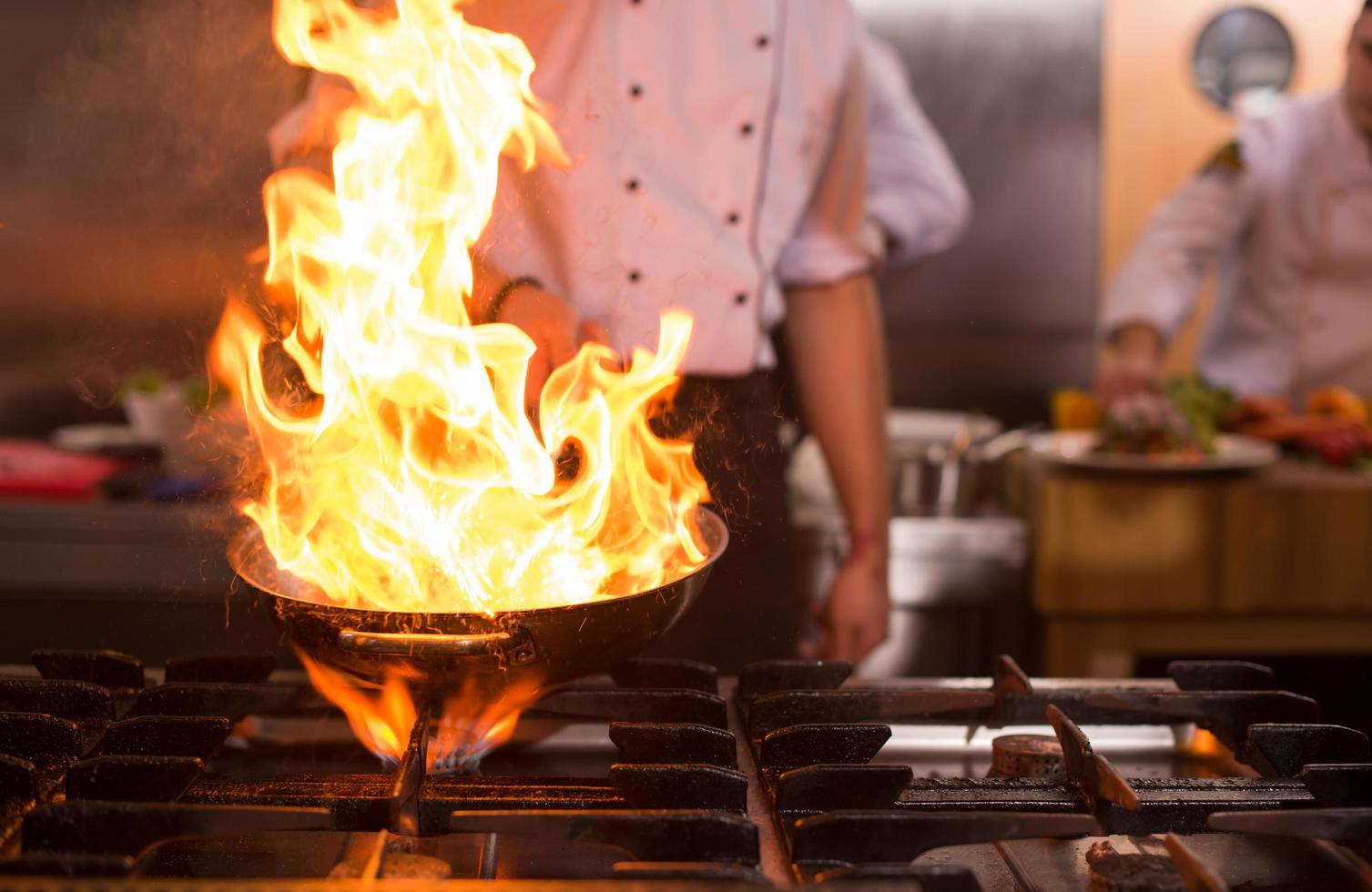 Koch macht Flamme auf Essen foto