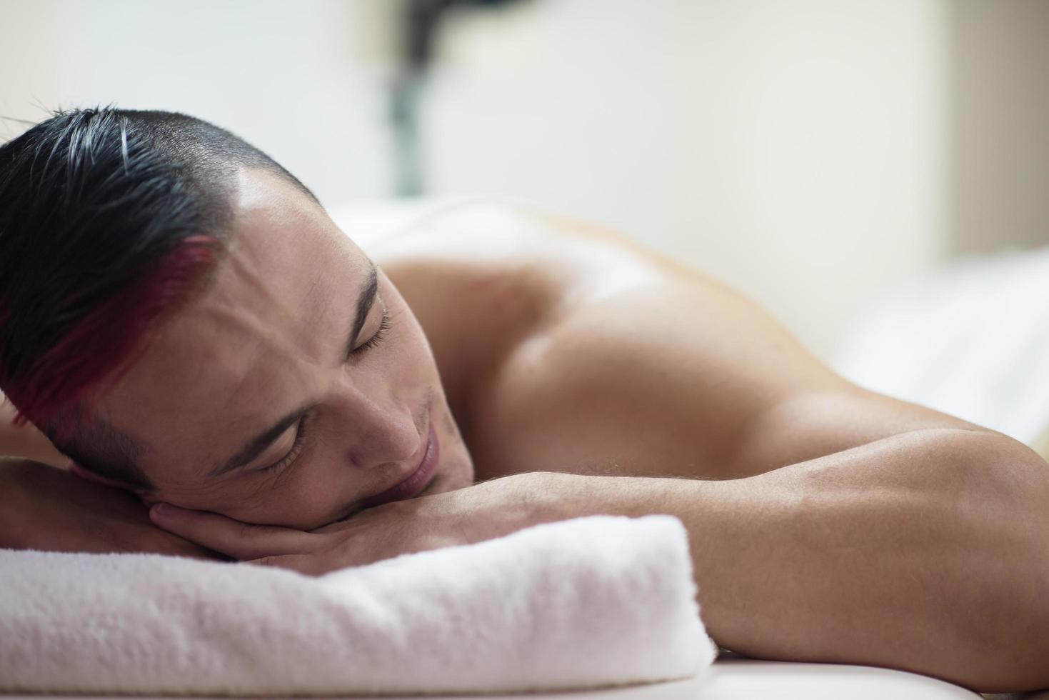 Schöner Mann, der sich in einem Spa-Massagezentrum ausruht foto