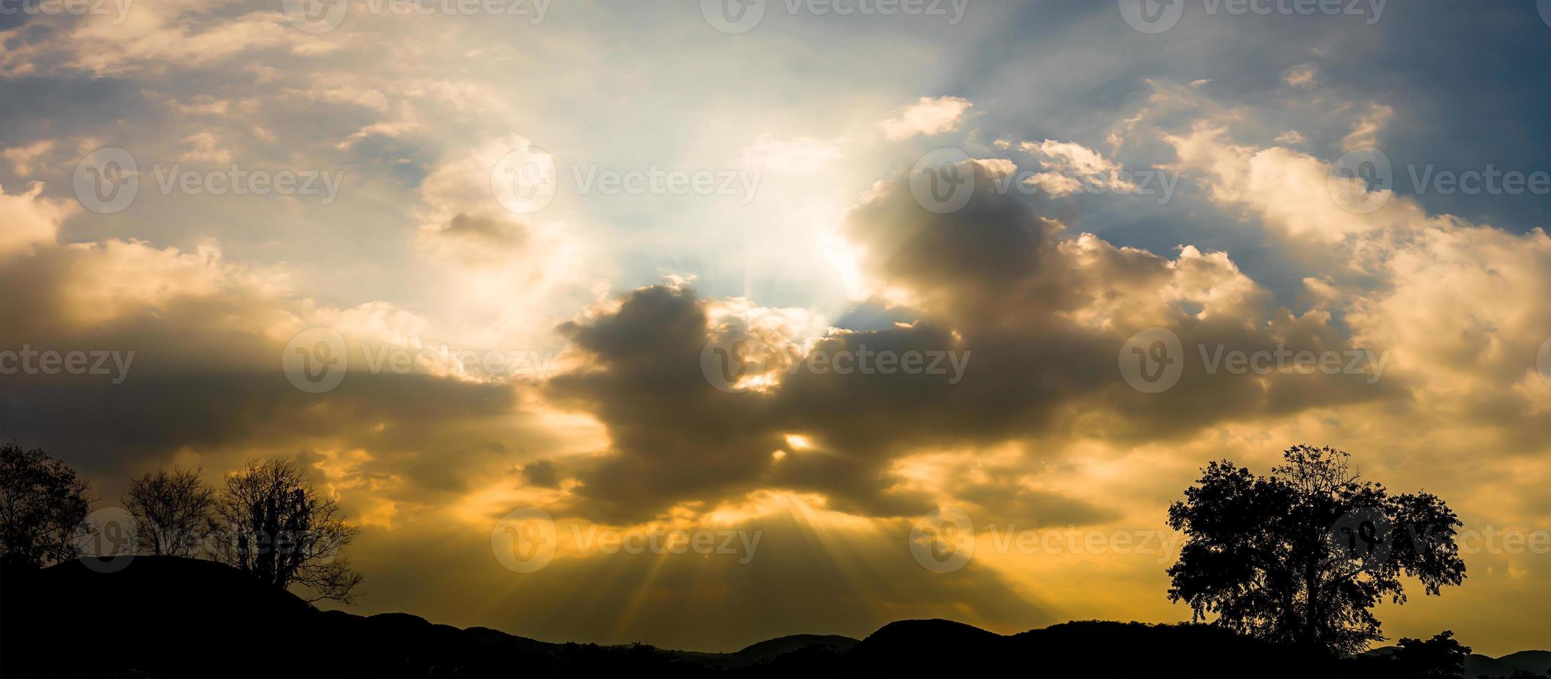 Panoramablick auf den Sonnenuntergang mit Wolken im Dämmerungshimmel mit Bergsilhouette foto