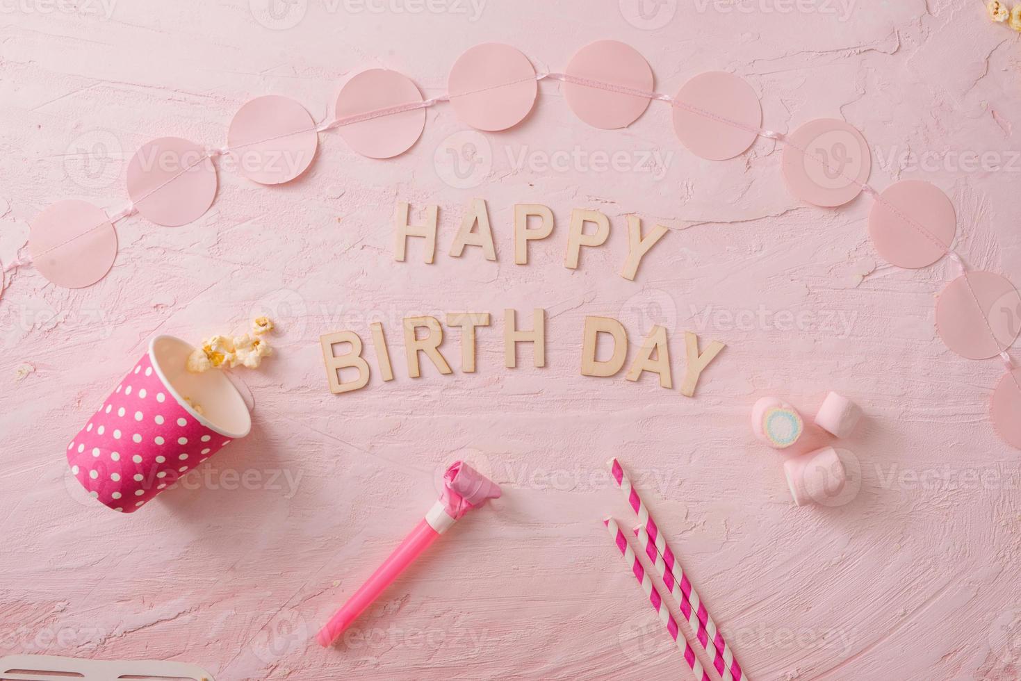 geburtstagsfeierhintergrund, konfettirand, süßigkeiten, lutscher und geschenk auf rosa oberfläche, kopierraum, draufsicht foto