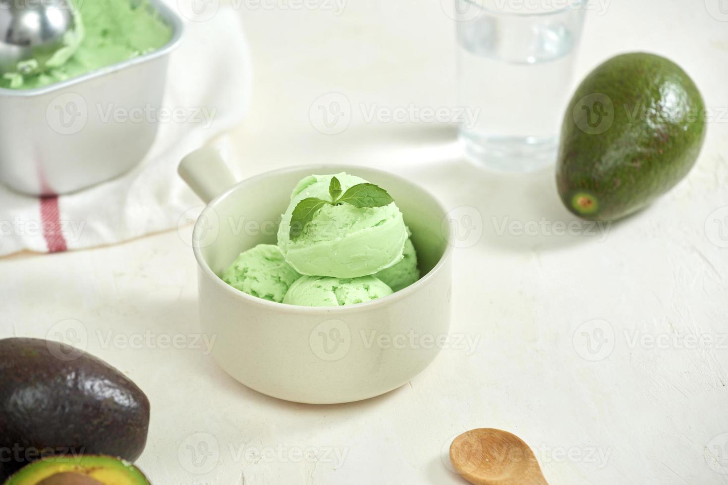Avocado-Eiskugeln auf einem weißen Teller, ein Löffel auf weißem Hintergrund. foto