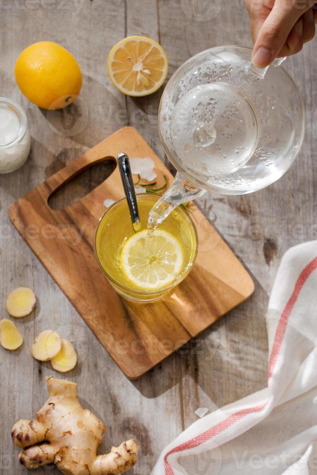 Tasse Ingwertee mit Zitrone. Tasse Ingwertee mit Zitrone. Glasbecher grüner heißer Tee auf Holztisch. geschnittene Zitronen auf einem Schneidebrett foto