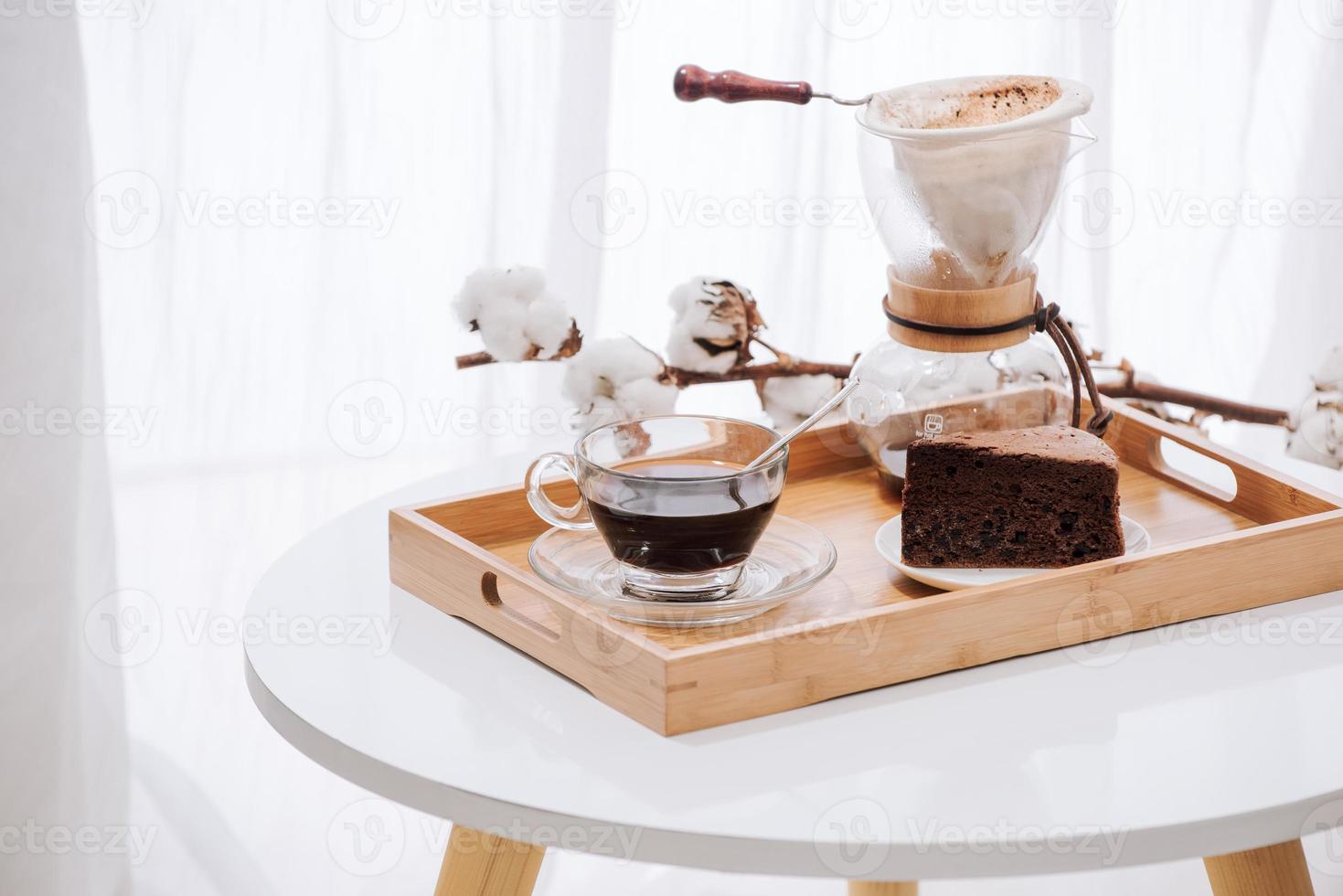 Tropfkaffee auf Holztablett mit Schokoladenkuchen. Kaffeezeit im Café mit Tageslicht foto