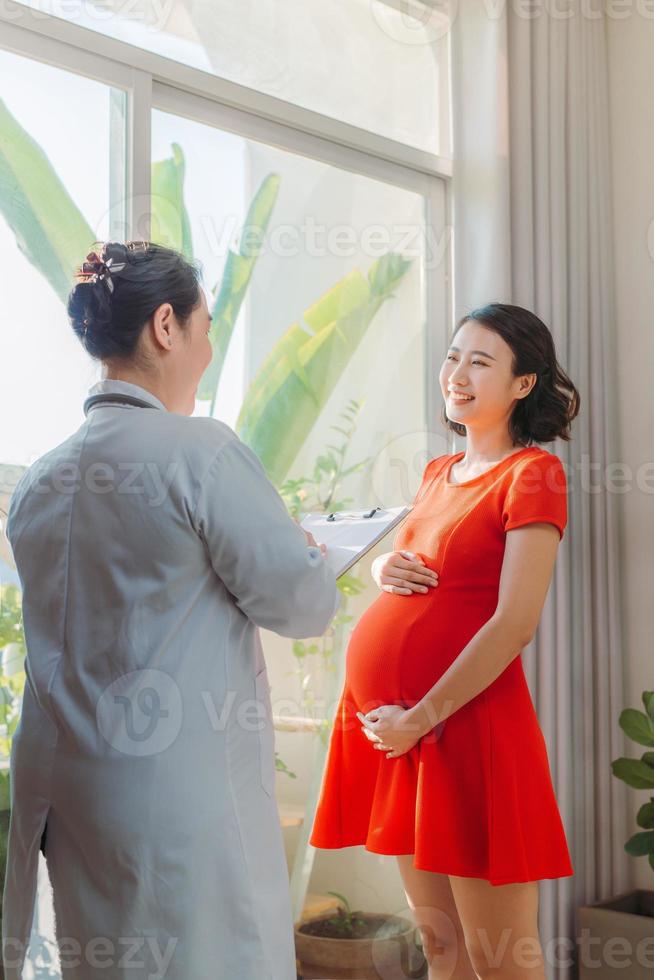 junge schwangere frau, die nach regelmäßiger untersuchung im krankenhaus auf verschreibung des arztes hört foto