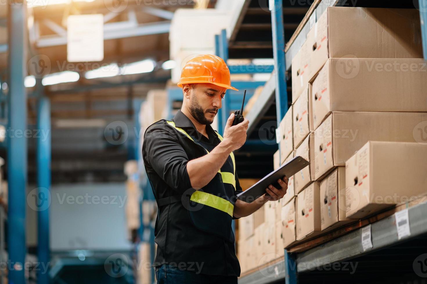 lagerarbeiter in uniform und notizblock, digitales tablet in den händen überprüft produktion. Lagerkonzept foto