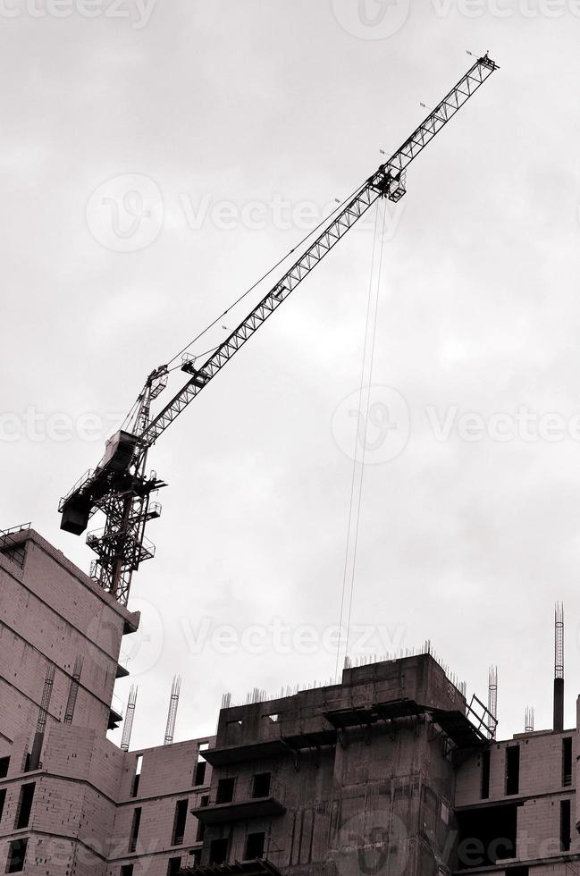 arbeitende hohe Kräne im Inneren mit hohen Gebäuden im Bau vor einem strahlend blauen Himmel. Fortschritt der Kran- und Bauarbeiten. Retro-Ton foto