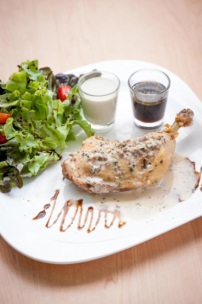 gebratenes Hähnchensteak auf dem Tisch mit Sauce und Salat foto