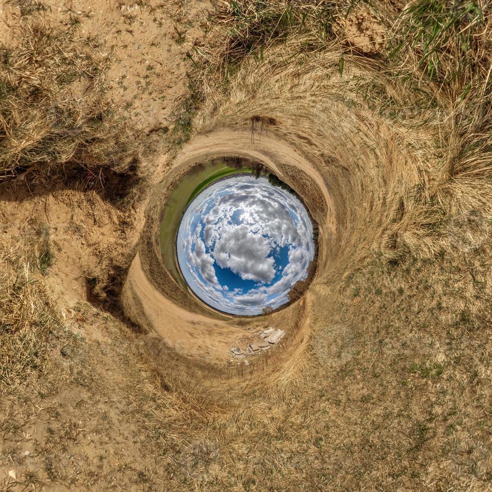 blauer Kugel kleiner Planet innerhalb des gelben Sandfeldhintergrundes. Krümmung des Raumes foto