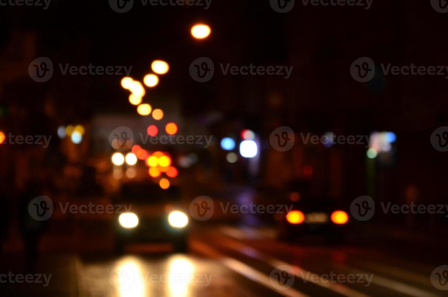 verschwommene Nachtszene des Verkehrs auf der Fahrbahn. defokussiertes Bild von Autos, die mit leuchtenden Scheinwerfern fahren. Bokeh-Kunst foto