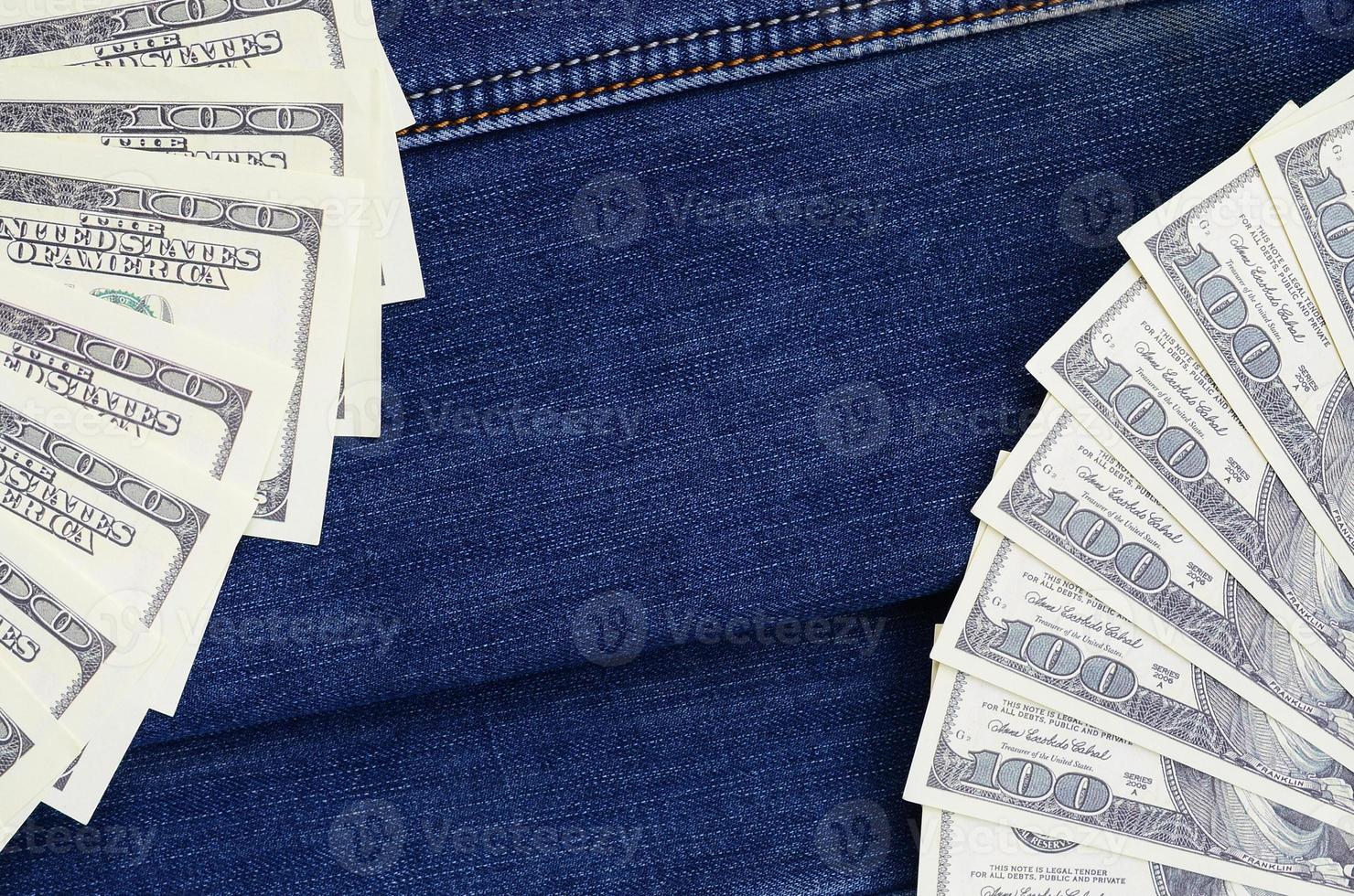 der fächer vieler us-dollar befindet sich auf einer dunklen jeansoberfläche. Hintergrundbild foto