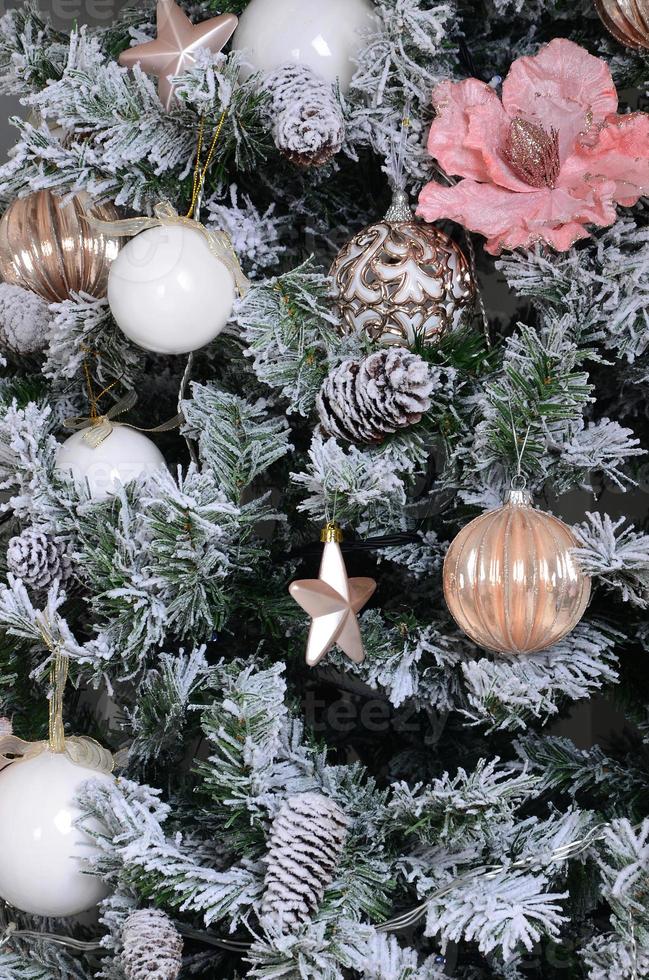 schmücken weihnachtsbaum hautnah. dekorationsbirne, schneebedeckter grüner tannenbaum, rosa weihnachtsspielzeug und lichter. verwenden sie für weihnachts- und neujahrsfeierhintergrund foto