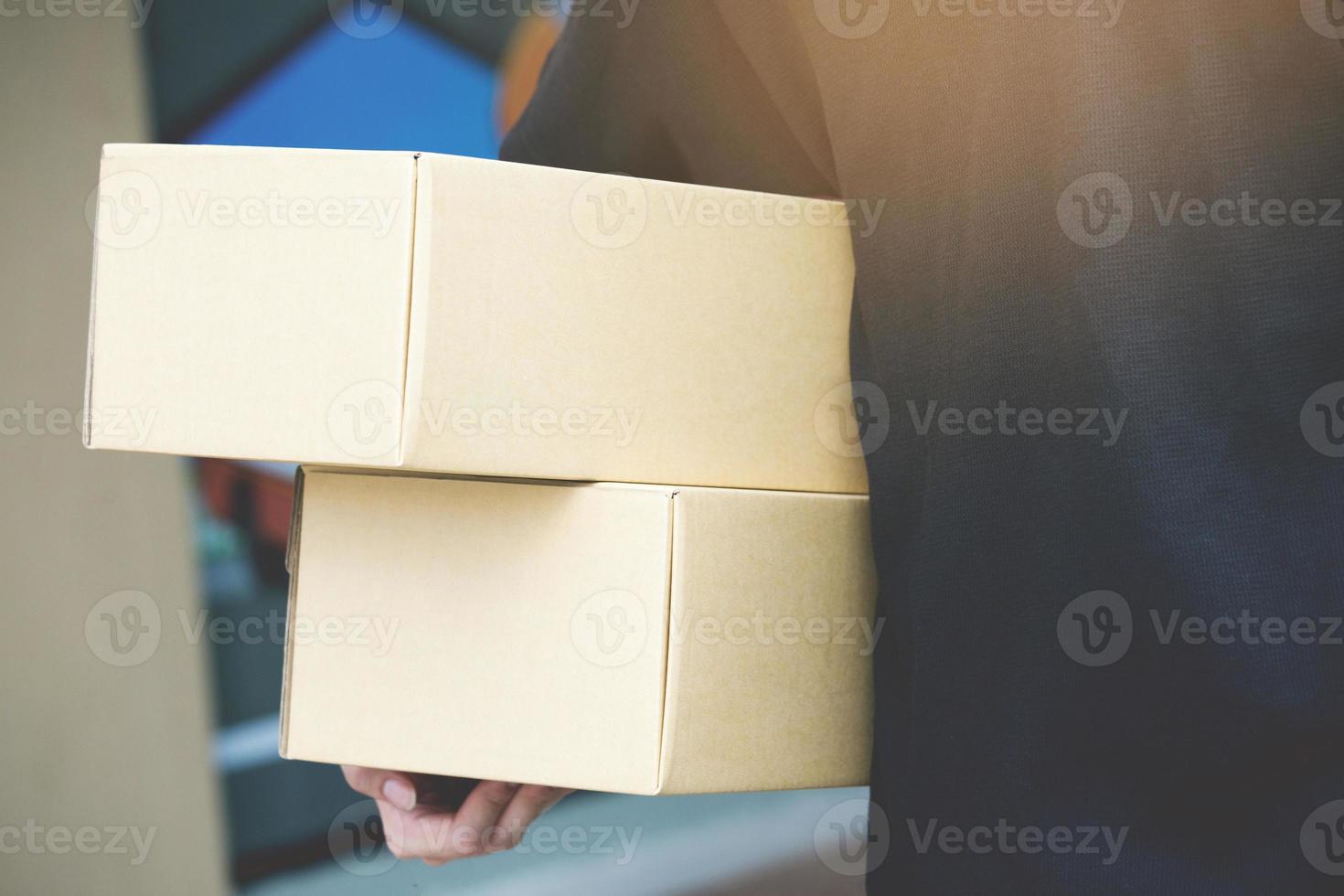 Paketzusteller eines Pakets über einen Dienst. bereiten Sie in der Hand vor, eine Lieferung von Kisten vom Zusteller zu versenden. foto