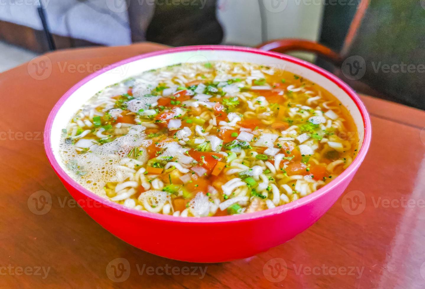 Instant-Nudelsuppe in rosa Schüssel auf braunem Holztisch. foto