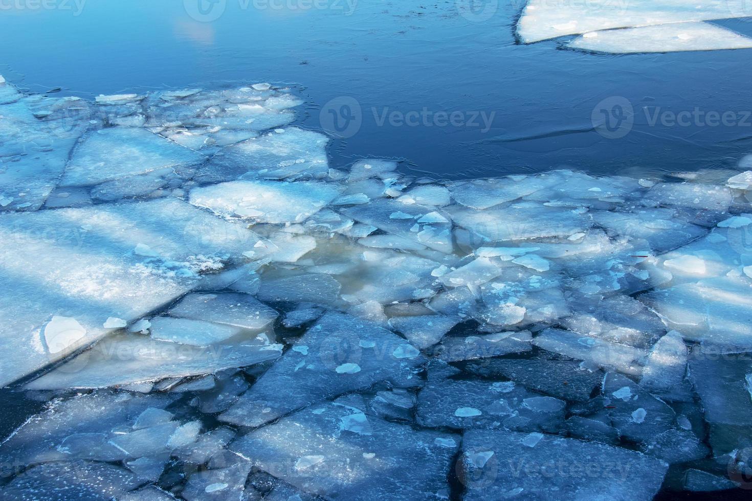 Winternaturhintergrund mit Eisblöcken auf gefrorenem Wasser im Frühjahr. abstrakter hintergrund von treibendem eis auf dem wasser foto