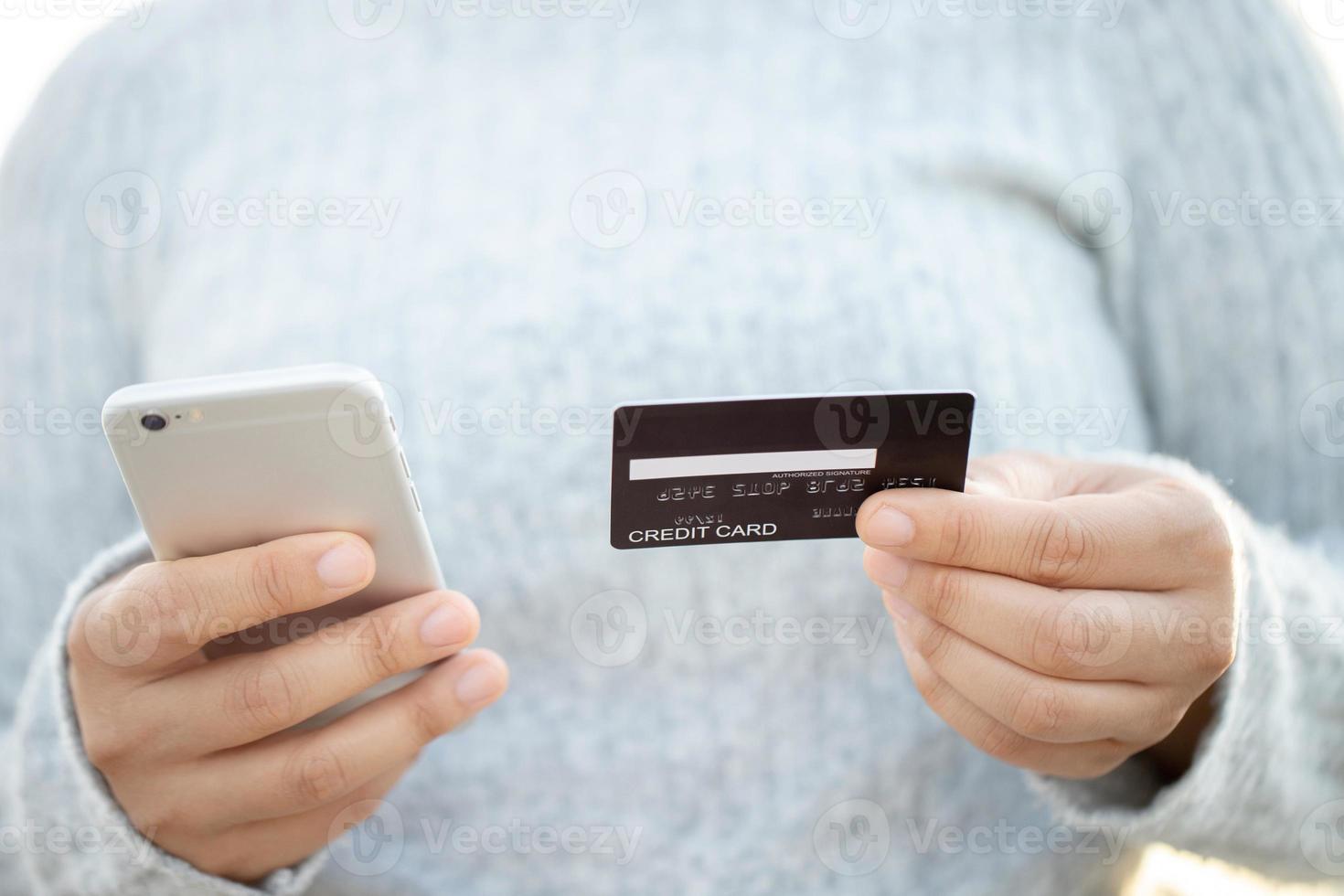 Eine Frau, die eine Kreditkarte verwendet, um Waren online mit einem Mobiltelefon zu bezahlen foto