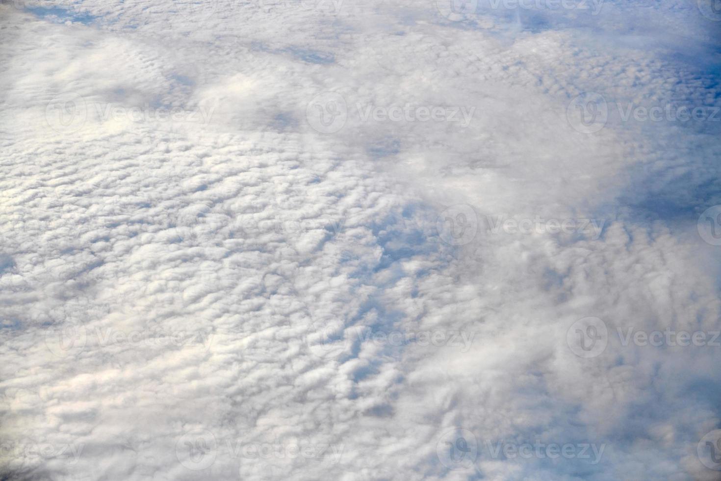 atemberaubender blick über die wolken aus dem flugzeugfenster, dicke weiße blaue wolken sehen aus wie weicher schaum foto
