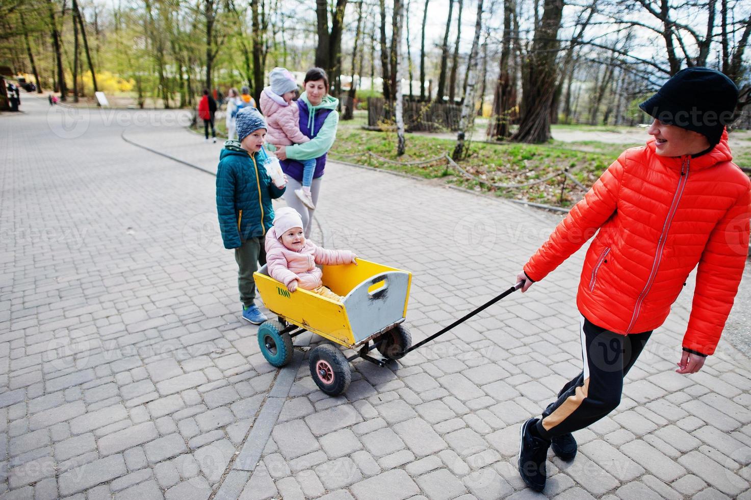 Mutter mit vier Kindern entdeckt und beobachtet Tiere im Zoo. Junge zieht Holzkarren. foto