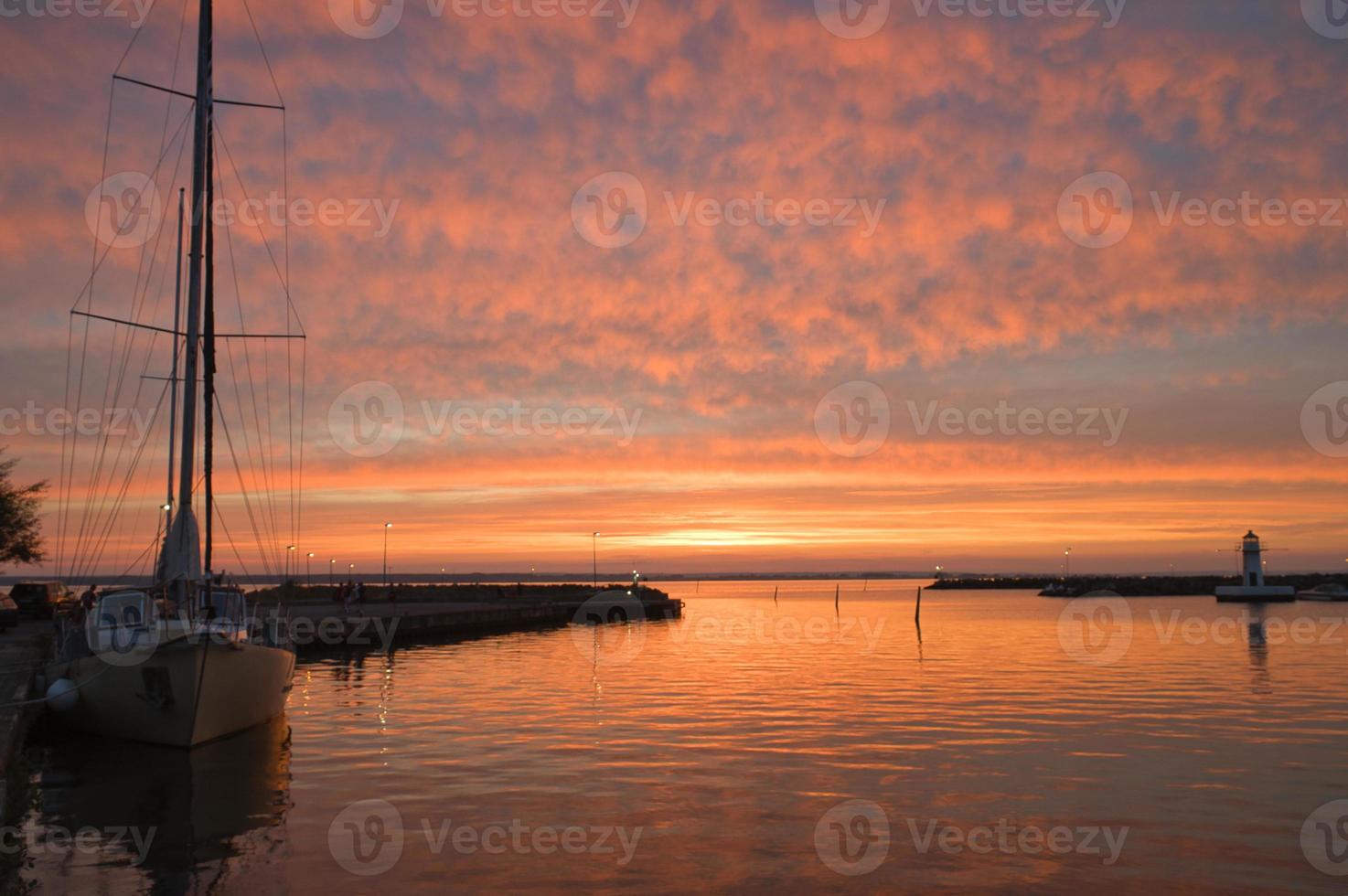 Segelschiff im Hafen des Vätternsees bei Sonnenuntergang. Leuchtturm im Hintergrund foto