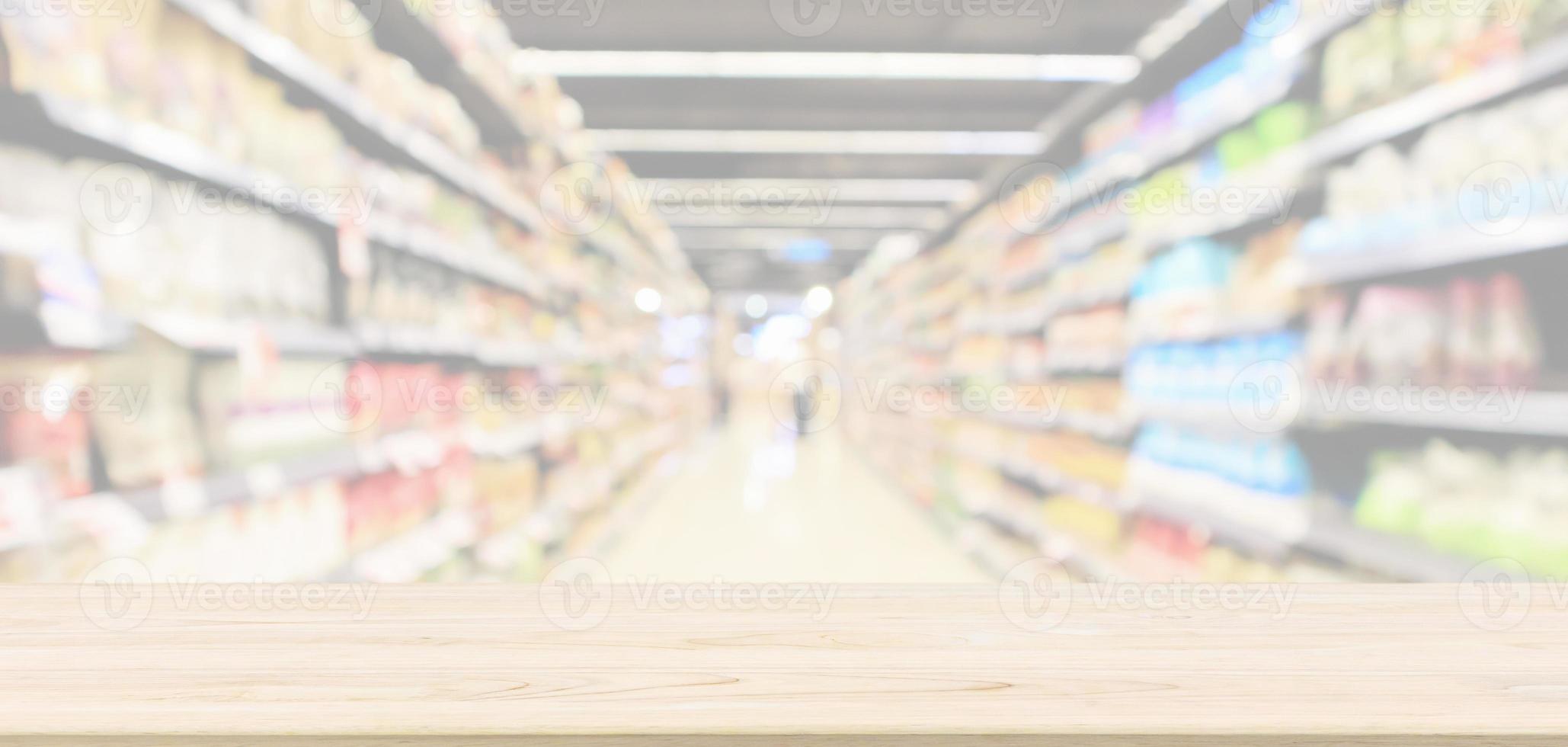 leere hölzerne tischplatte mit supermarktgang mit produktregalen innen defokussierter unschärfehintergrund foto