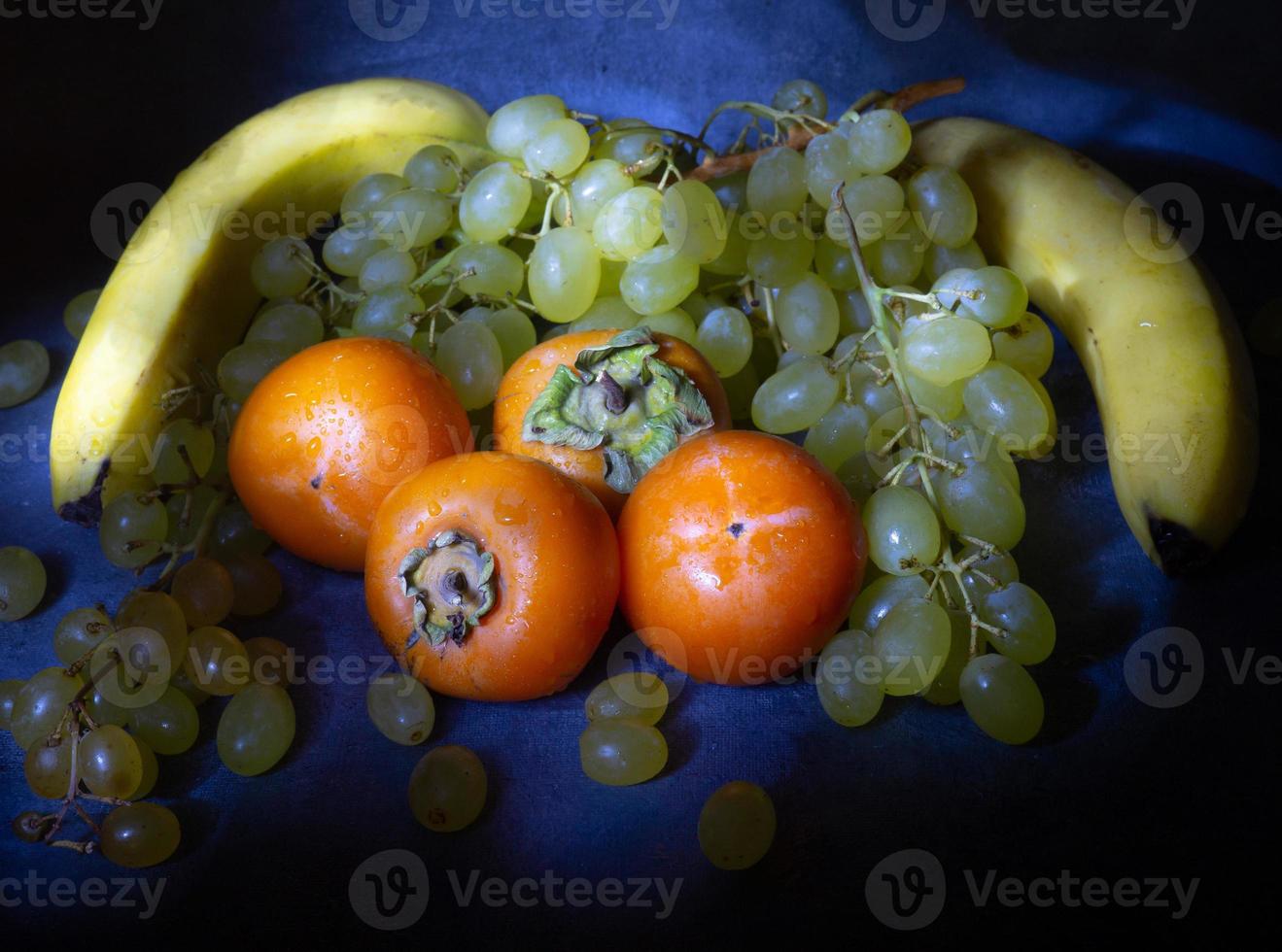 Stillleben mit Früchten. Apfel, Kaki und Trauben auf schwarzem Hintergrund. Persimone Kamille. Apfel Gala. gesundes Essen. Wassertropfen auf der Frucht foto